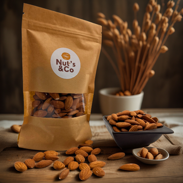 Bol d'amandes décortiquées à côté d’un paquet avec une étiquette NutsAndCo contenant des amandes décortiquées, avec des amandes étalées par terre.