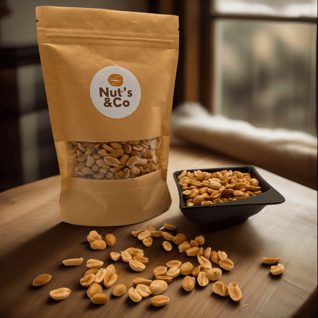 Bol de cacahuètes à côté d’un paquet avec une étiquette NutsAndCo contenant des cacahuètes, avec des cacahuètes étalées par terre.