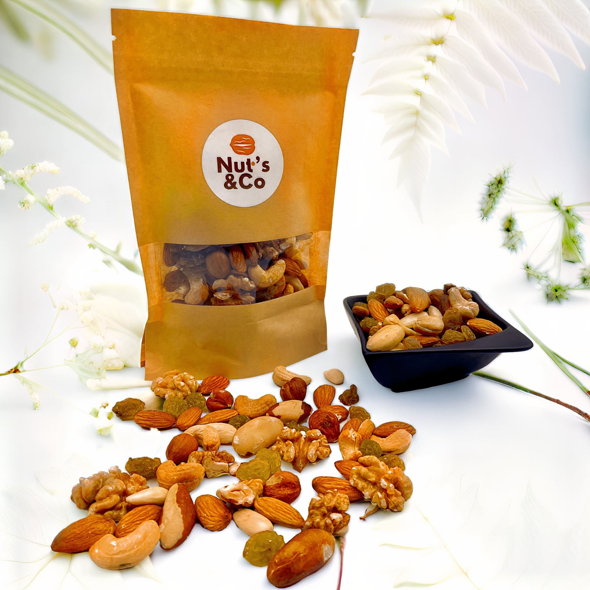 Bol de mix Vitalité & Énergie à côté d’un paquet avec une étiquette NutsAndCo contenant le mix Vitalité & Énergie, avec des ingrédients étalés par terre.